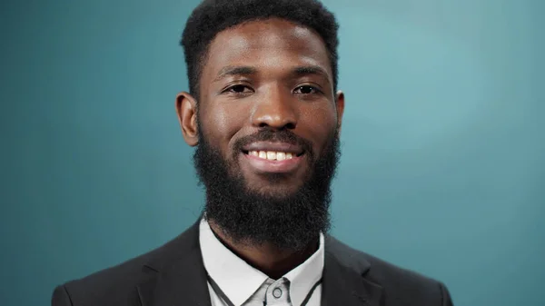 A young handsome black bearded man in a tuxedo is smiling and looking at the camera full size