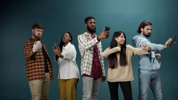 Um grupo multirracial de melhores amigos está sorrindo e tirando fotos em seus telefones — Fotografia de Stock