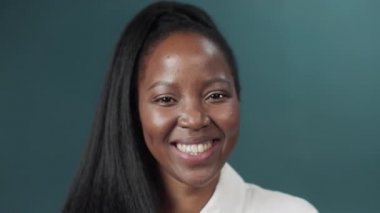 Siyah kadın, uzun saçlı, yeşil stüdyo arka planında poz veren, gülümseyen.