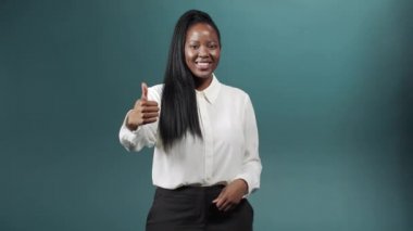 Neşeli bir Afrikalı kadın başparmağını kaldırıyor ve gülümsüyor.
