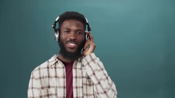 Een Afrikaanse jongeman in een wit shirt luistert naar muziek en danst. — Stockvideo