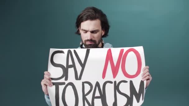 An adult white man in a blue hoodie is raising a poster against racism in slow motion — Stock Video