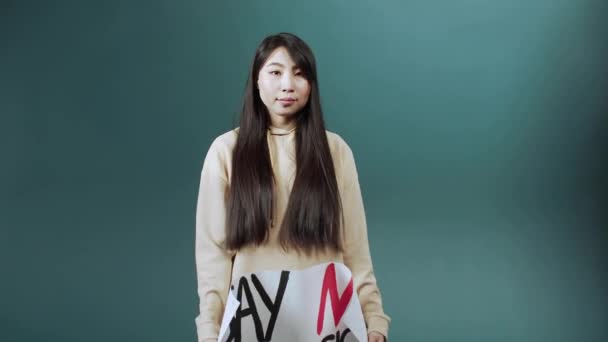 一位穿着米黄色连帽衫的漂亮的亚裔女士正在展示一张反对种族主义和走开的海报 — 图库视频影像