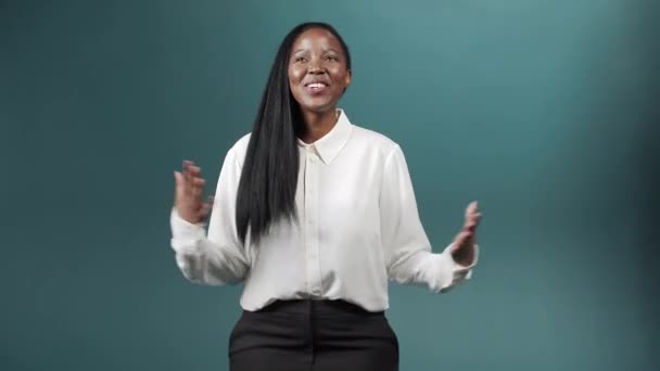 Ein attraktives, fröhliches afrikanisches Mädchen mit langen Haaren spricht in die Kamera, lächelt und gestikuliert — Stockvideo