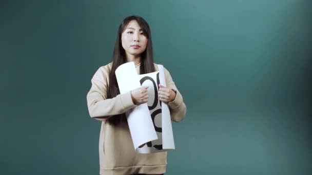 Серьезная азиатка ходит и показывает плакат против расизма — стоковое видео