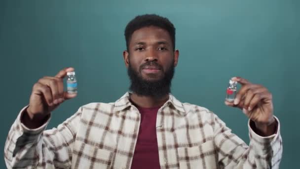 Привлекательный молодой черный мужчина выбирает левую ампулу с вакциной — стоковое видео