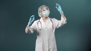 Özel tıp üniformalı çekici genç bir doktor iki ampulü aşıyla karşılaştırmaya çalışır ve doğru olanı seçer.