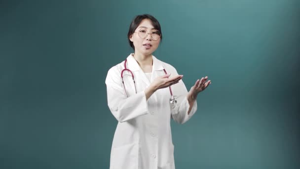 Um médico alegre atraente em um vestido médico branco está falando com a câmera e gesticulando — Vídeo de Stock