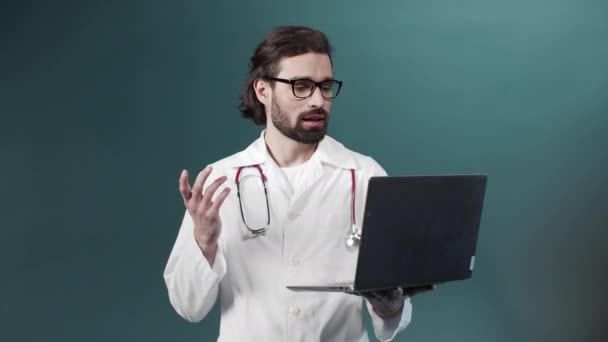Genç siyah sakallı bir doktor hastasıyla internetten video görüşmesi yapıyor. — Stok video