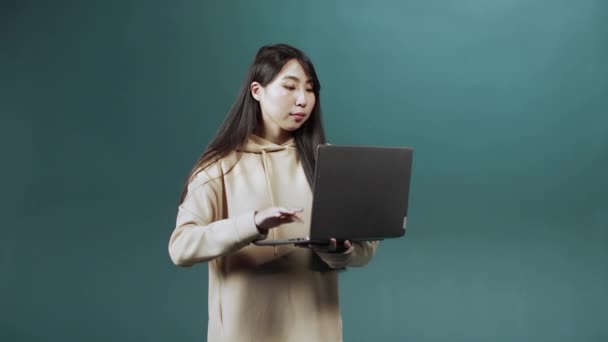 Bej kapüşonlu güzel bir kız bilgisayarını arkadaşlarıyla sohbet etmek ve gülümsemek için kullanıyor. — Stok video