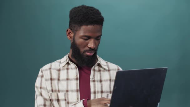 Młody czarny facet ujawnia poważne nastawienie trzymając laptopa — Wideo stockowe