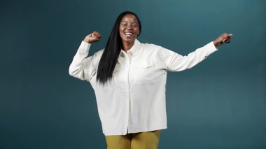 Yeşil arka planda ilham verici yüz ifadesiyle dans eden güzel siyah kadın.