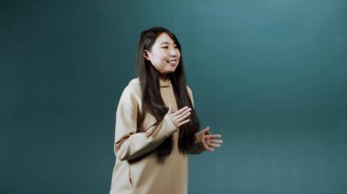 Genç Asyalı bir bayan ağır çekimde zevkle dans ediyor.