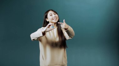 Genç ve tatlı Asyalı bir bayan koronavirüse karşı bir ampul aşı tutuyor ve baş parmağını kaldırıyor.