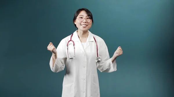 Um médico alegre atraente em um vestido médico branco está falando com a câmera, sorrindo e gesticulando — Fotografia de Stock