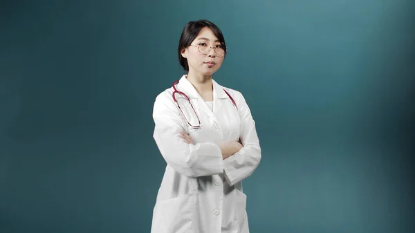 Een serieuze dokter in een medisch uniform kruist haar armen en kijkt naar de camera. — Stockfoto