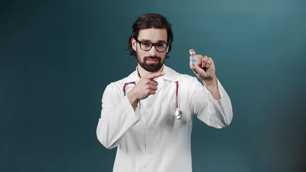 An attractive young doctor smiles and shows an ampule with vaccine — Stock Photo, Image