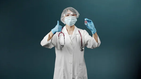 Özel tıp üniformalı çekici genç bir doktor iki ampulü aşıyla karşılaştırmaya çalışır ve doğru olanı seçer. — Stok fotoğraf