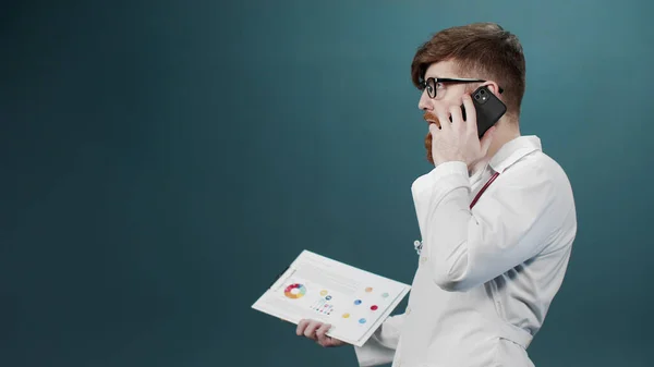 Um homem de vestido branco fala ao telefone e sai com um tablet na mão — Fotografia de Stock