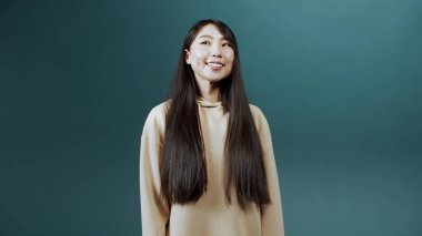 Güzel bir kız yeşil arka planda mutlu, şaşkın ve heyecanlı bir şekilde poz verir.