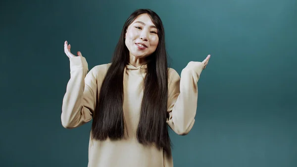 Una atractiva chica china alegre con el pelo largo está hablando con la cámara, sonriendo y haciendo gestos —  Fotos de Stock