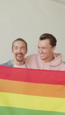 İki yakışıklı genç adam Igbt bayrağı gösteriyor, birbirlerine bakıp gülümsüyorlar. Yüksek kaliteli FullHD görüntüler