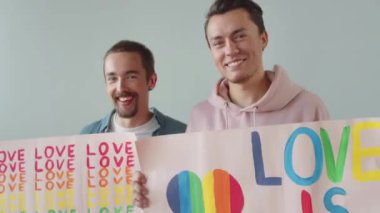 İki mutlu Igbt adamı ayakta kameraya bakıyor ve posterleri gösteriyor. Yaklaş. Yüksek kalite 4k görüntü