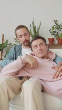 İki Igbt adamı oturma odasındaki kanepede birlikte oturuyor, konuşuyor ve el ele tutuşuyorlar. Yüksek kaliteli FullHD görüntüler