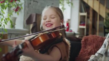 Kız keman çalıyor. Annesine gülümsüyor ve birlikte gülüyorlar. Yüksek kalite 4k görüntü