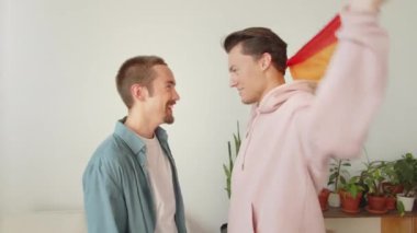 Igbt bayrağıyla kaplanmış iki genç adam yan yana durur ve biraz dans ederler. Yüksek kaliteli FullHD görüntüler