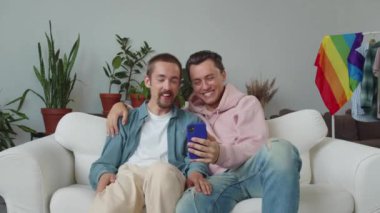 İki çekici genç lgbt erkeği video görüşmesinde arkadaşlarıyla sohbetlerini bitirir, ikisi de hareket eder ve gülümserler. Yüksek kaliteli FullHD görüntüler