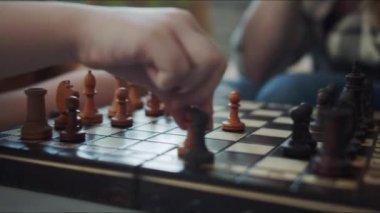 Annem çocuğuyla satranç oynar. Kız beyaz piyonu hareket ettirir ve siyah taşa saldırır. Kadın bir atla karşılık veriyor. Yüksek kalite 4k görüntü