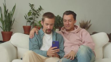 İki çekici genç lgbt erkeği video görüşmesinde arkadaşlarıyla sohbetlerini bitirir, ikisi de hareket eder ve gülümserler. Yüksek kaliteli FullHD görüntüler