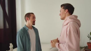 Genç Igbt erkekleri birbirleriyle konuşuyorlar, perdelerin yanında duruyorlar ve gülüyorlar. Yüksek kaliteli FullHD görüntüler