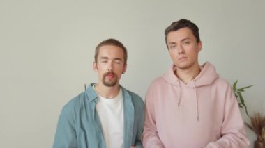İki yakışıklı genç adam lgbt bayrağını salladı, kameraya ciddi ciddi bak ve başını salla, yaklaş. Yüksek kaliteli FullHD görüntüler