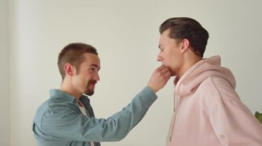 Eğlenceli sohbetler sırasında, yan yana dururken, iki genç lgbt erkeği birbirlerinin kıyafetlerini düzeltiyorlar. Yüksek kaliteli FullHD görüntüler