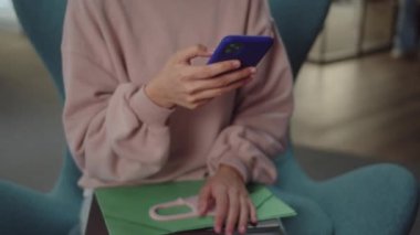 Genç bir kız öğrenci sandalyede oturur, teneffüste internette yazılar okur. Yüksek kaliteli FullHD görüntüler