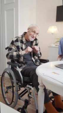 Tekerlekli sandalyedeki bir adam kulaklıkla hoş müzik dinler. Mutlu ve heyecanlı görünüyor. Kız da dizüstü bilgisayarda şarkıları değiştirip gülümsüyor. Yüksek kaliteli FullHD görüntüler