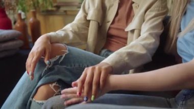 İki çekici kız oturma odasında kanepede oturuyor, birbirleriyle konuşuyorlar, el ele tutuşuyorlar. Yüksek kaliteli FullHD görüntüler