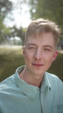 Mavi gömlekli genç yakışıklı bir adam kameraya bakıyor, gözlerini kırpıyor ve düşünüyor. Yüksek kaliteli FullHD görüntüler