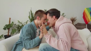 Lgbt adamları oturma odasındaki kanepede yan yana oturup el ele tutuşarak konuşuyorlar. Yüksek kalite 4k görüntü