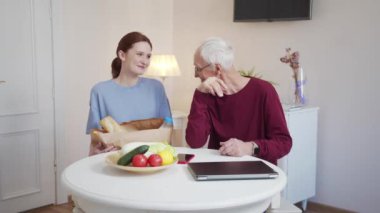 Mutlu büyükbaba ve tatlı torunu büyük yuvarlak bir masada oturup neşeyle gülümserler. Yüksek kalite 4k görüntü