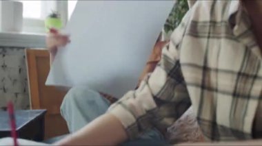 Kadın eline bir kalem alır ve önüne bir kağıt parçası koyar. Çizmeye başlıyor ve kıza kalemi nasıl tutacağını söylüyor. Yüksek kalite 4k görüntü