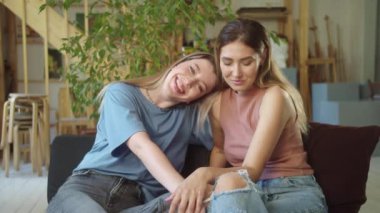 İki çekici genç bayan stüdyoda kanepede birlikte oturuyor, kameraya bakıyor ve gülümsüyorlar. Yüksek kalite 4k görüntü