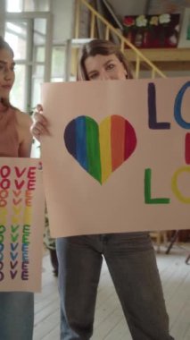 İki güzel genç kız ellerinde Igbt posterleriyle stüdyoda duruyor ve kameraya bakıyor. Yüksek kaliteli FullHD görüntüler