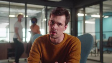 Genç bir erkek öğrenci üniversitede sandalyede oturuyor ve kameraya konuşuyor, yavaş çekimde kapatın. Yüksek kalite 4k görüntü