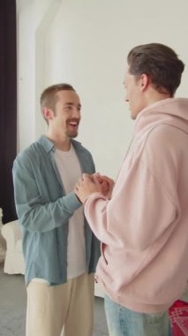 İki Igbt adamı oturma odasında birlikte duruyorlar, birbirleriyle konuşuyorlar ve el ele tutuşuyorlar. Yüksek kaliteli FullHD görüntüler