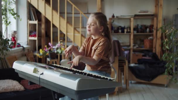 Malé Dítě Sedí Samo Velké Místnosti Hraje Syntezátor Vystrčí Jazyk — Stock video