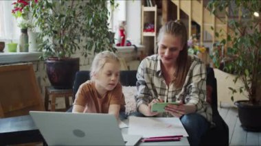 Çocuk kalemlerle kağıda resim çizer. Öğretmen yakınlarda oturuyor ve ilham almak için internetteki kız resimlerini gösteriyor. Yüksek kalite 4k görüntü