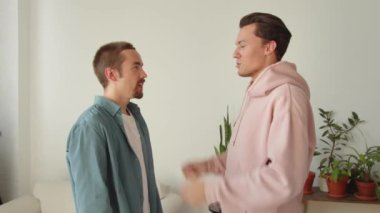 Eğlenceli sohbetler sırasında, yan yana dururken, iki genç lgbt erkeği birbirlerinin kıyafetlerini düzeltiyorlar. Yüksek kaliteli FullHD görüntüler